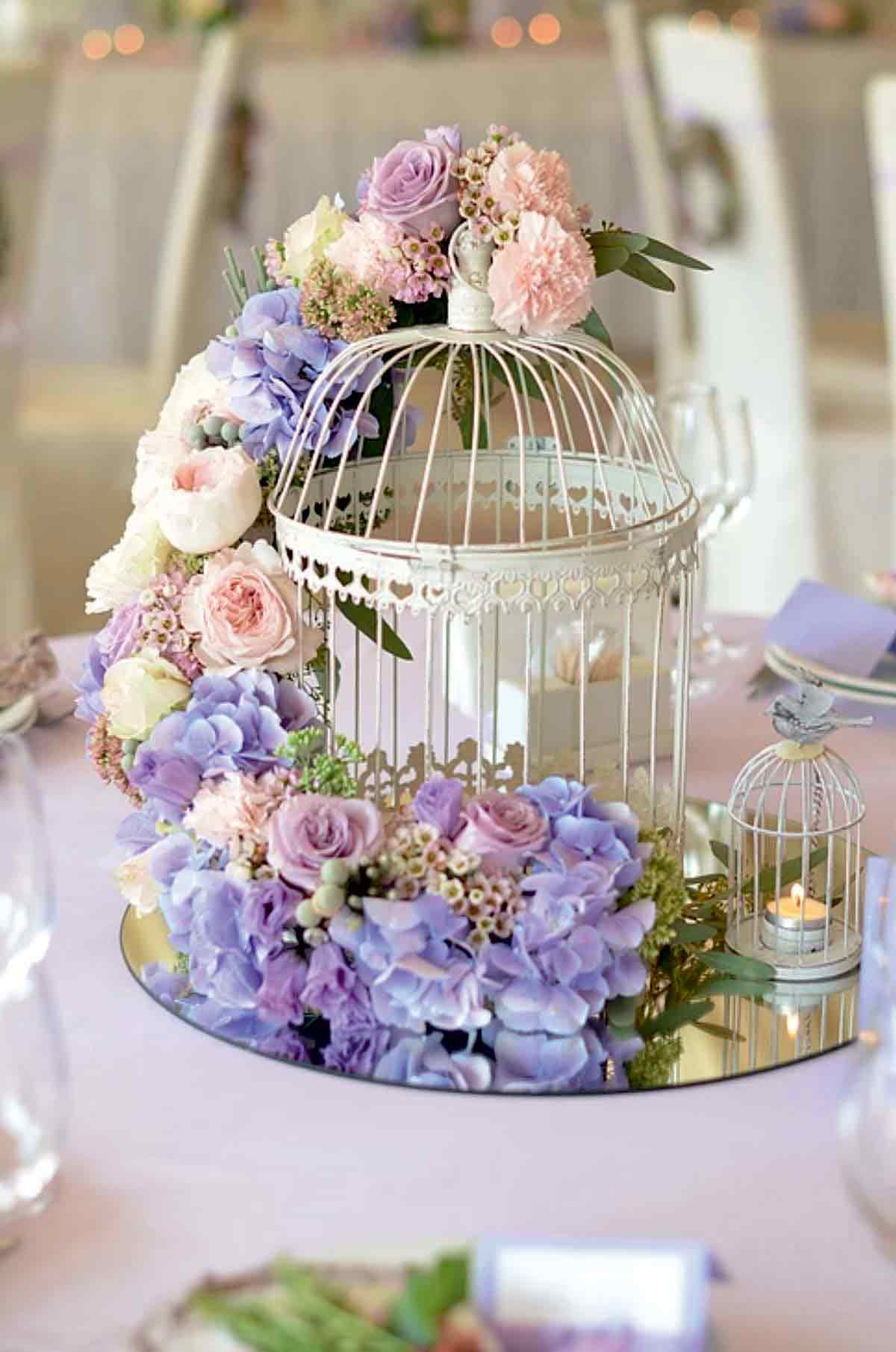 Bouquet violet et blanc avec cage d'oiseau sur une table